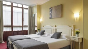 A hotel room with two beds, a large window with curtains, a wall-mounted painting, and bedside lamps. - Iraipe Ongi Hotel (Oñati)