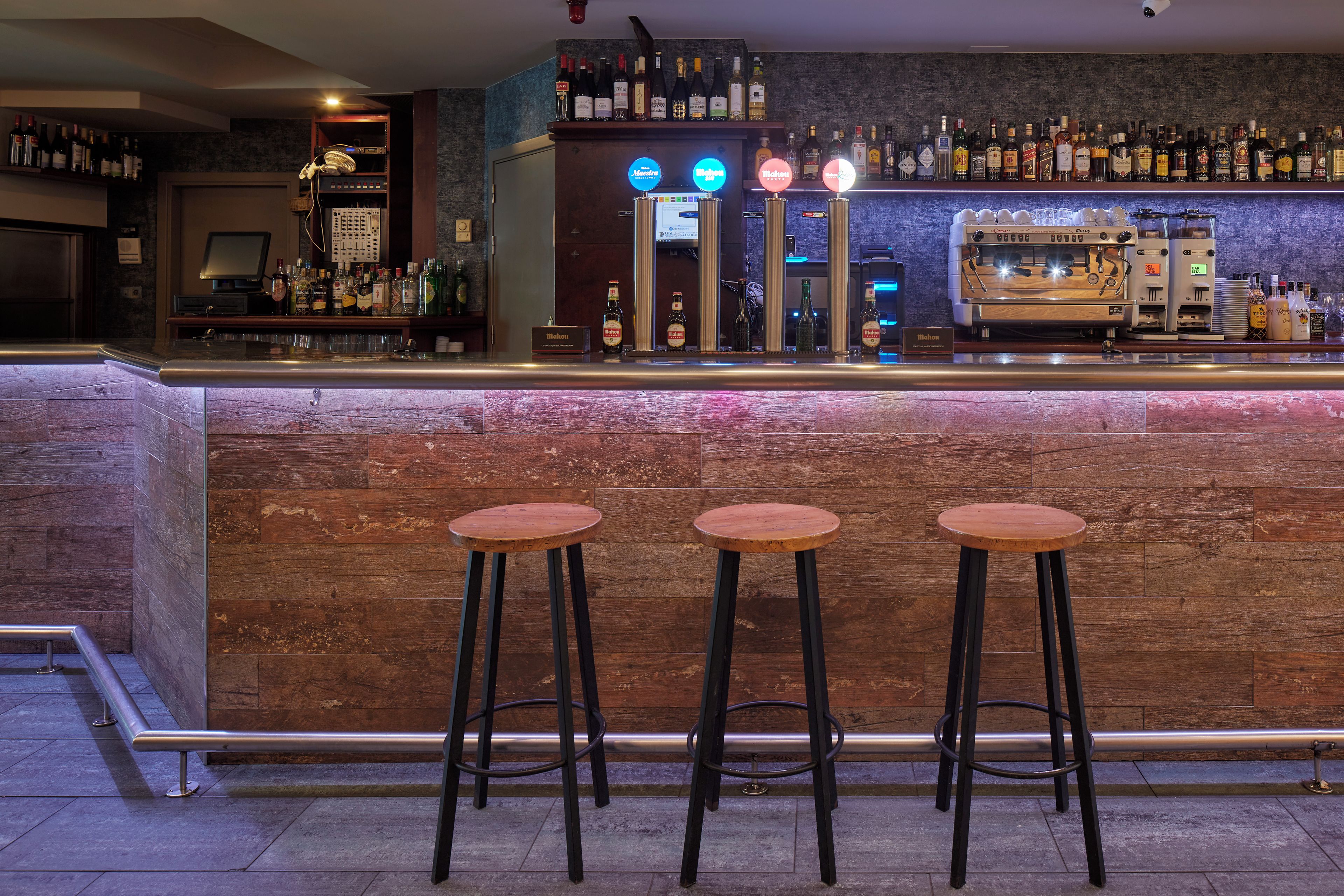 Een bar met krukken, een toonbank en een divers aanbod aan flessen.