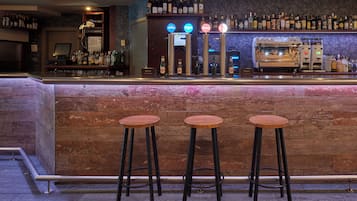 Een bar met krukken, een toonbank en een divers aanbod aan flessen.