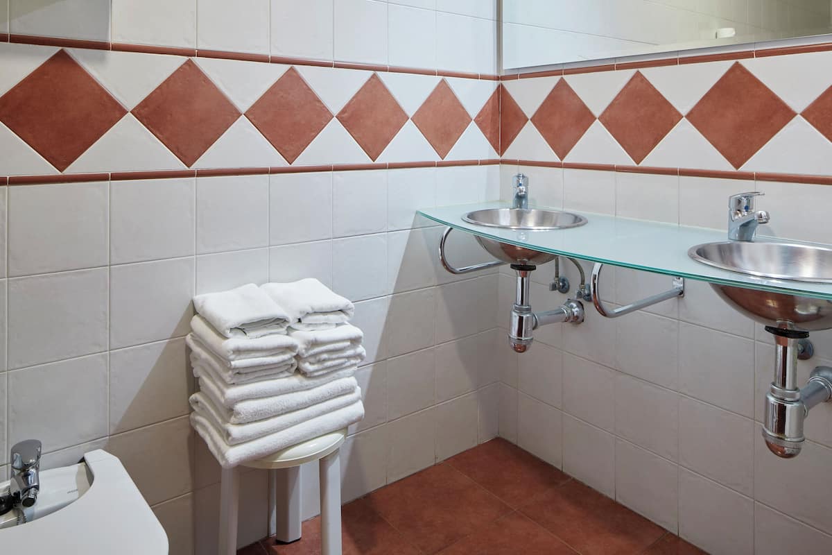 Une salle de bain avec des carreaux blancs, un lavabo en verre, un miroir et un porte-serviettes.