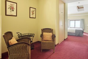 A hotel room with a red carpet, wicker furniture, and two framed floral pictures on the wall. - Iraipe Ongi Hotel (Oñati)