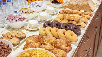 A buffet with a variety of food items including pastries, bread, and beverages.