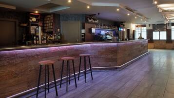 A bar area with a counter, stools, and a variety of bottles.