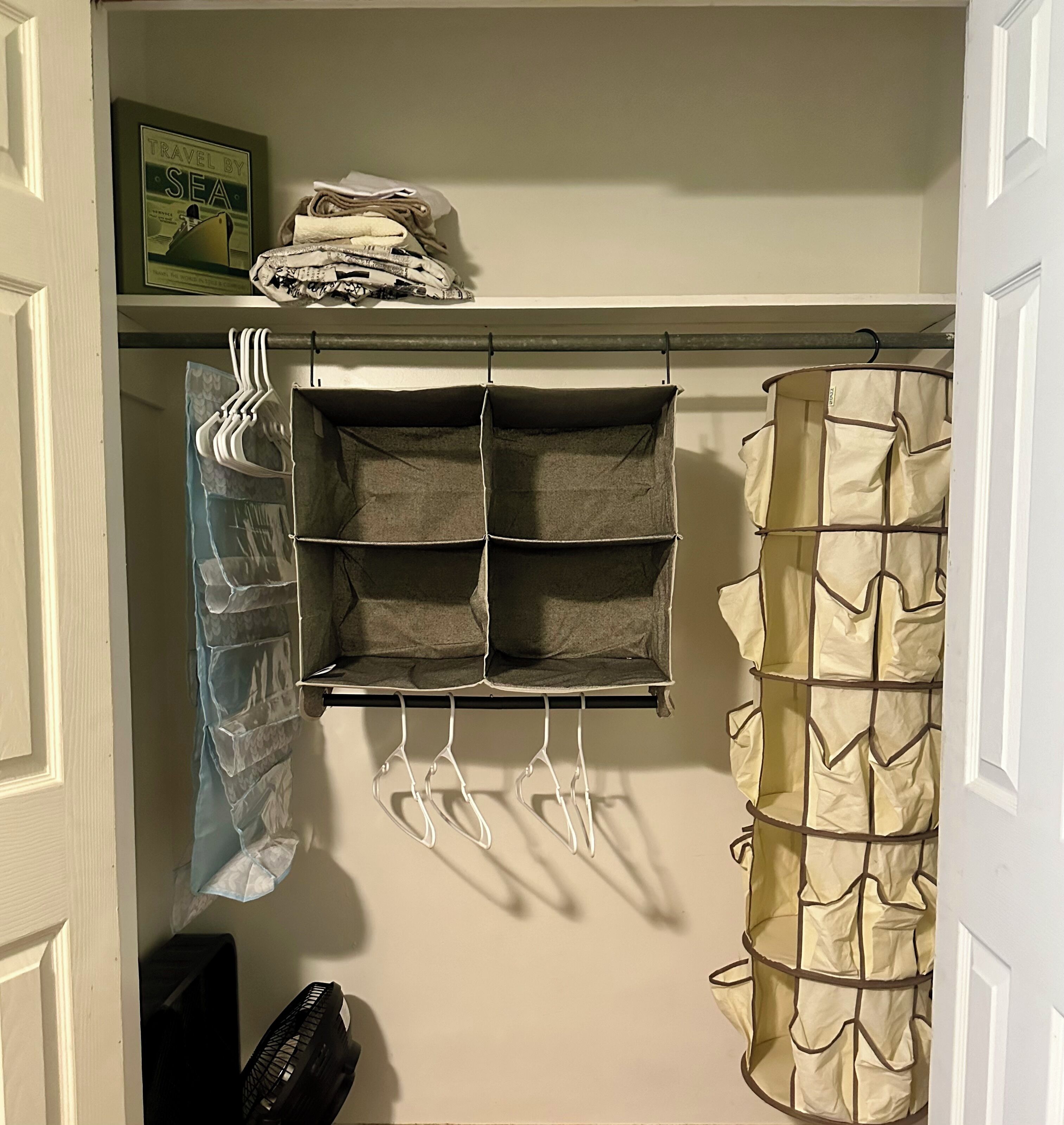 A closet with a hanging rack, shelves, and a folded item on top.