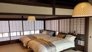 Et traditionelt japansk soveværelse med tatami-gulv, en lav platformsseng med mørkt træstel og en væg af shoji-skærme.