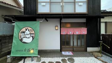 A traditional Japanese building with a green banner featuring a fox and a white building.