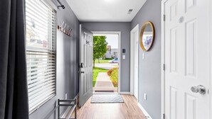 A hallway with a door leading outside, a mirror on the wall, and a set of coat hooks. - Splendid 4 Bed/2.5 Bath- Near Speedway (Indianapolis)