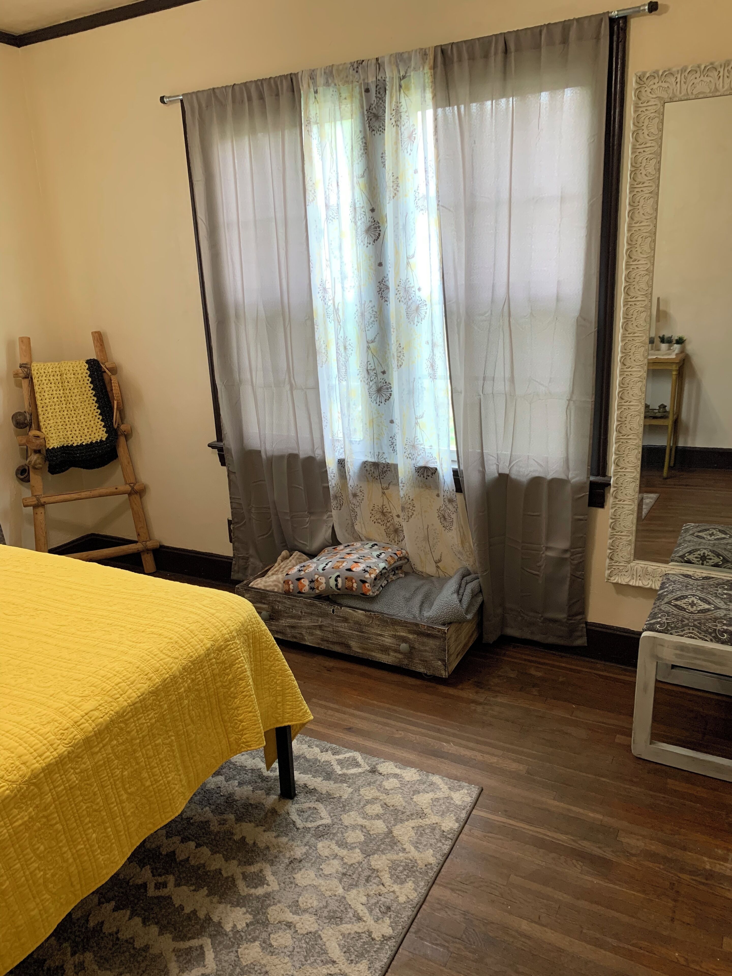 Ein Zimmer mit einem Bett, einem kleinen Sofa, einem Holzstuhl und einem Spiegel.