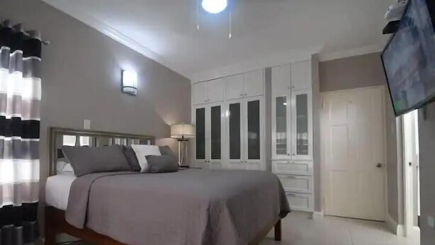 A bedroom with a bed, wardrobe, and a TV. - Captivating 1-Bed  Ravinia Apartment in Kingston (Kingston)