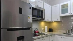 A modern kitchen with white cabinets, stainless steel appliances, and a tiled backsplash. - Captivating 1-Bed  Ravinia Apartment in Kingston (Kingston)