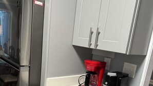 A compact kitchen with a stainless steel refrigerator, a red coffee maker, and grey cabinets. - Mountain View Home (Cave Spring)