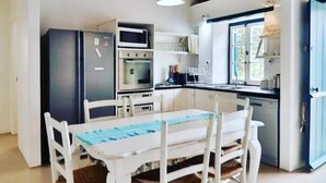 Cocina compacta con una mesa y sillas, microondas, horno y refrigerador.