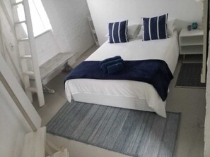 Cozy retreat with a neatly made bed, a nightstand, and a reading lamp.