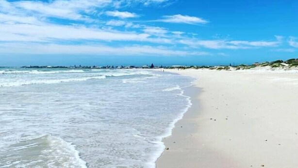 Una playa con cielo despejado y olas suaves.