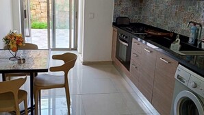 A modern kitchen with a dining area, a washing machine, and a view of the outdoors. - Tilal Fanar resort, pools, generator included (Fanar)