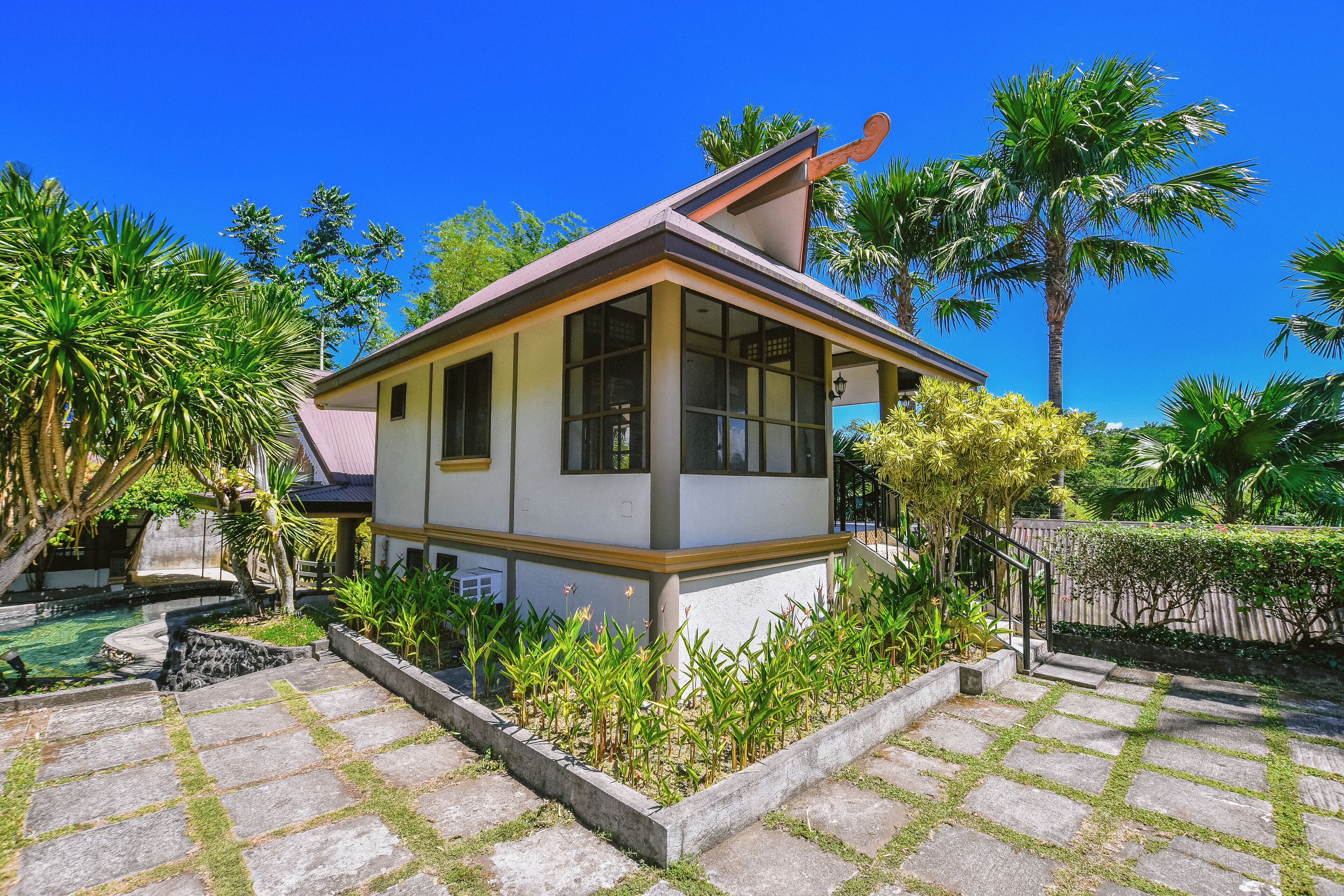 A small, single-story house with a tiled patio and a garden.
