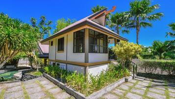 A small, single-story house with a tiled patio and a garden.
