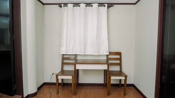 Una habitación con un banco de madera, una cortina blanca y un enchufe.