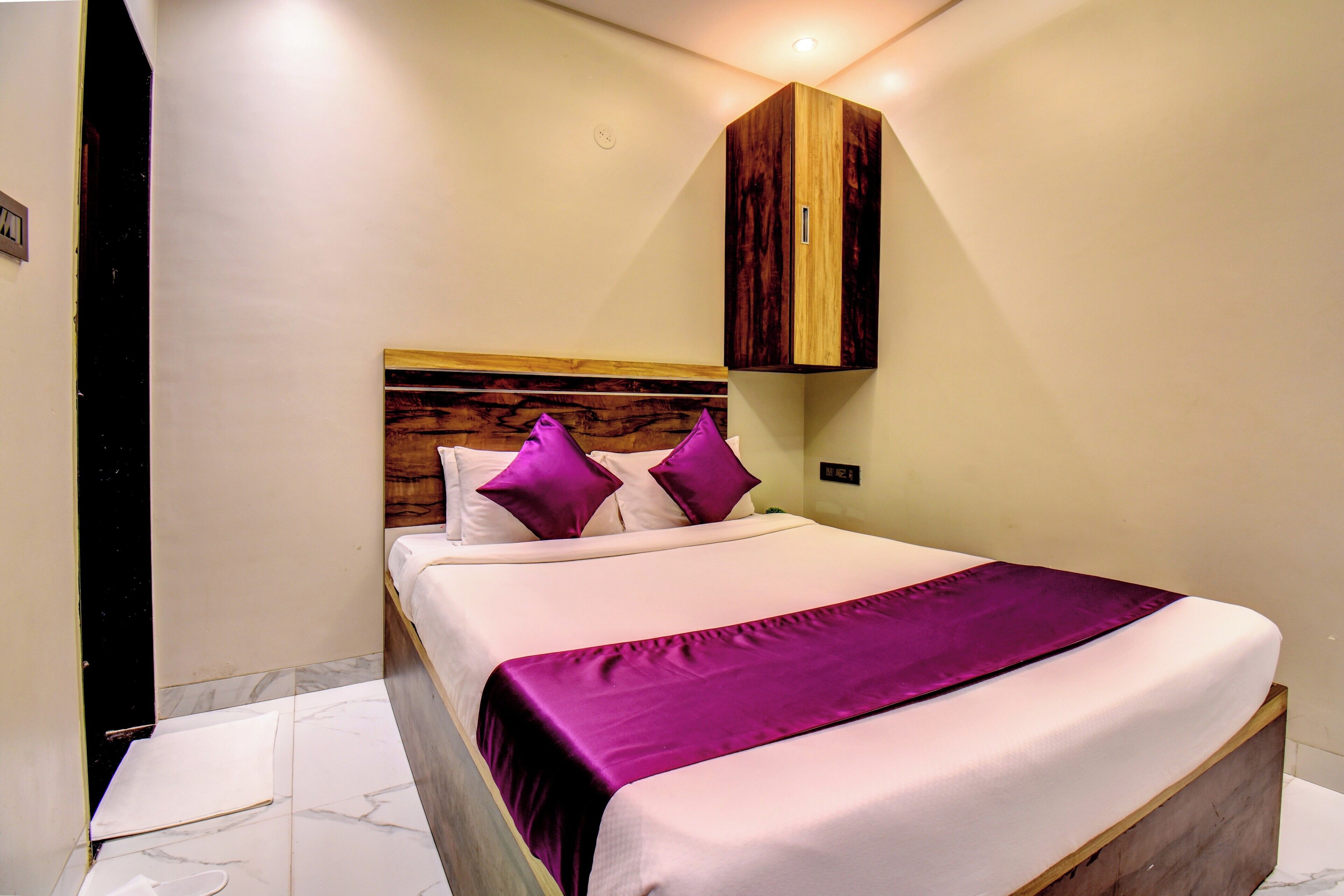 Una cama bien hecha con cabecera de madera, colcha morada y almohadas a juego.