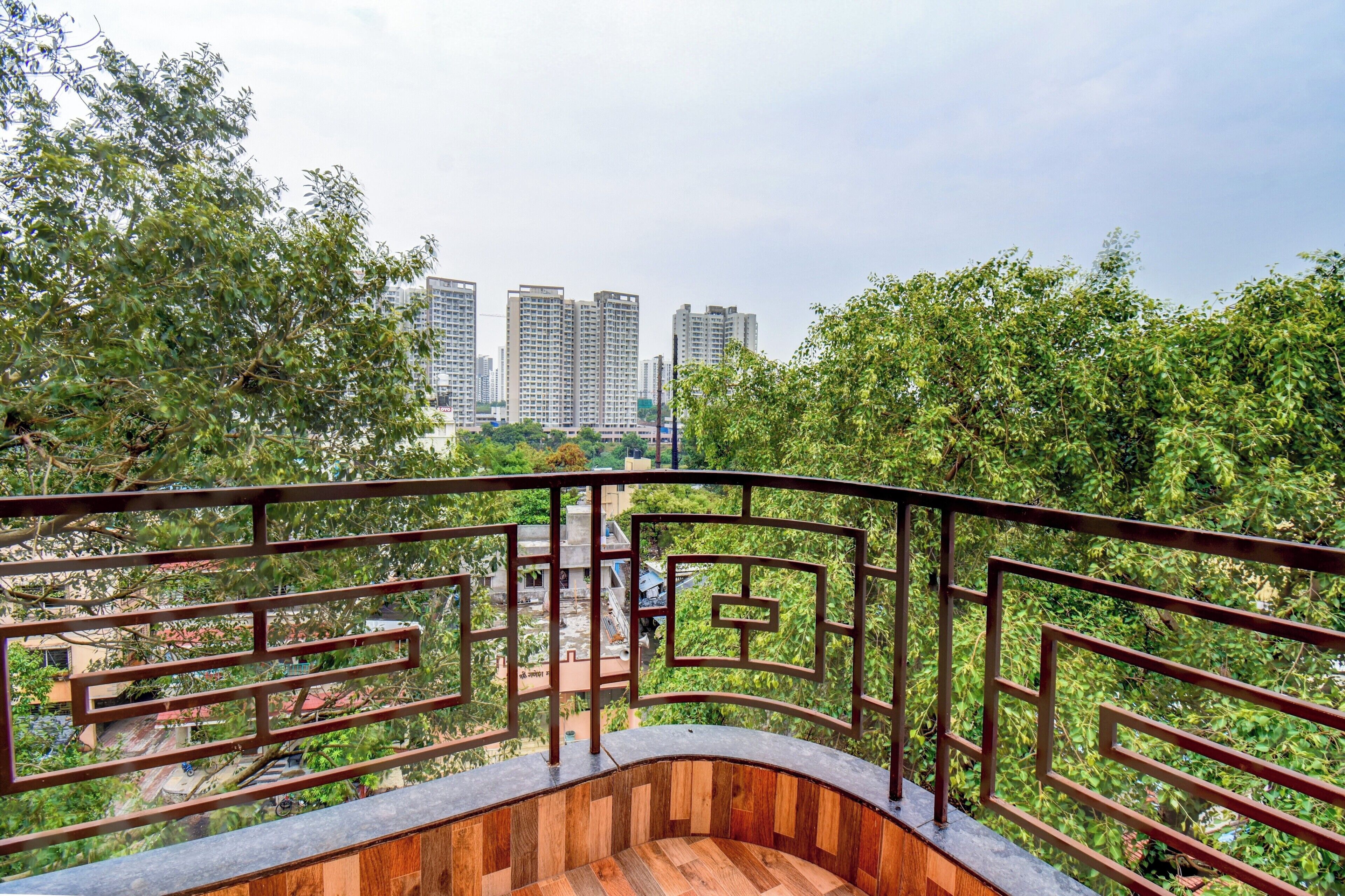 A balcony with a view of high-rise buildings and dense greenery.