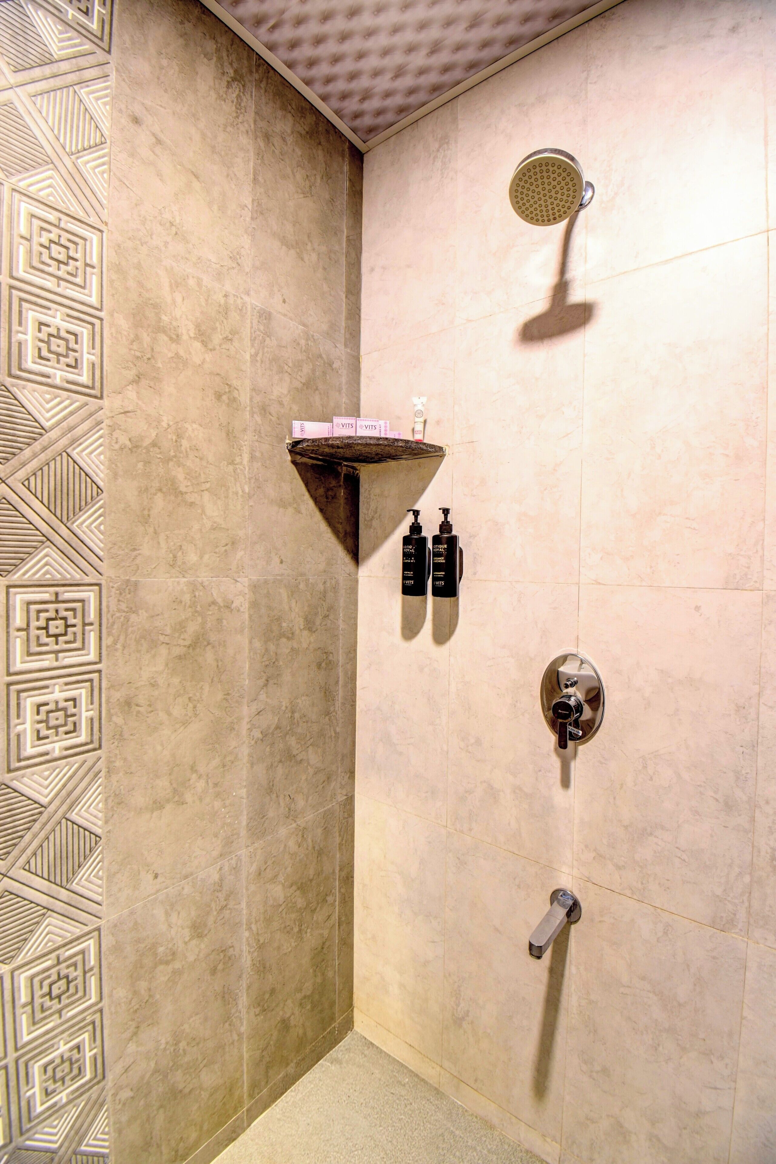 A shower area with a handheld showerhead, a shelf with toiletries, and a towel rack.