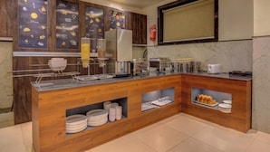 Una cocina moderna con armarios de madera, un refrigerador de acero inoxidable y un mostrador tipo buffet con platos y tazones.