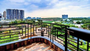Un balcón con vista a un paisaje urbano, que incluye edificios altos y zonas verdes.