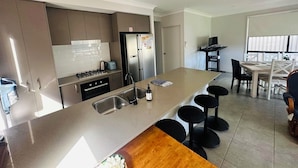 Een moderne keuken met een centraal eiland, roestvrijstalen apparatuur en een eetgedeelte met een tafel en stoelen.