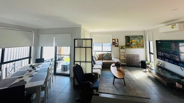 Een moderne woonkamer met een eethoek, een bank, een salontafel en een televisie.