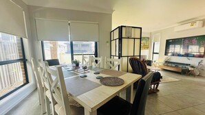 Een eetgedeelte met een houten tafel en stoelen, een televisie en uitzicht op een balkon.