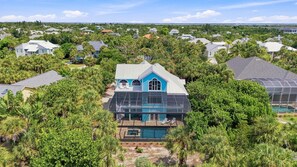 A residential property with a large house featuring a prominent blue facade, a swimming pool, and lush surrounding vegetation.