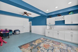 A room with a kitchenette, white cabinets, a ceiling fan, and a colorful rug. - Huge savings for March April and May! (Sanibel)
