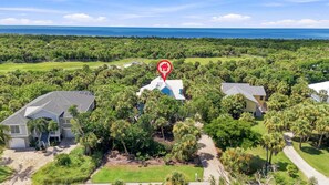 A residential area with multiple houses surrounded by lush greenery and a view of the ocean. - Huge savings for March April and May! (Sanibel)