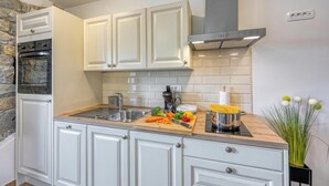 A kitchen with white cabinets, a stone accent wall, a stainless steel range hood, and a wooden countertop with various food items. - Istrian Casa Pr Marici Relaxing Vineyard, Koper, Slovenia (Koper)