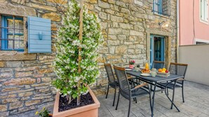 Un bâtiment en pierre avec une table et des chaises, une plante en pot et une porte.