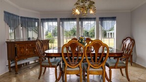 Une salle à manger avec une table ronde, six chaises en bois et un lustre.