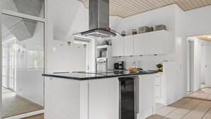 Une cuisine moderne avec des meubles blancs, un plan de travail noir et un four encastré.