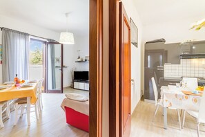 Un appartamento moderno con zona pranzo, cucina e soggiorno con TV.