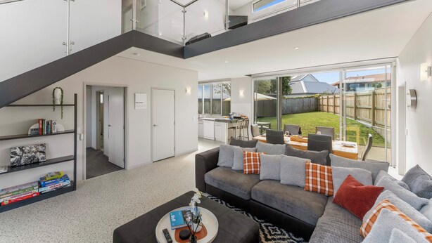 A modern living room with a staircase, a sofa set, a coffee table, and a view of the backyard. - Lake Taupo Gem (Taupo)