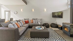 A modern living room with a sectional sofa, a flat-screen TV, a fireplace, and a patterned rug. - Lake Taupo Gem (Taupo)