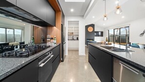 A modern kitchen with a central island, stainless steel appliances, and pendant lighting. - CatchN'Relax with Hot Tub (Taupo)