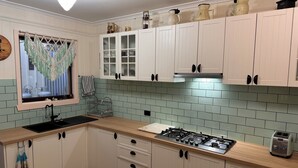 A kitchen with white cabinets, a gas stove, a kettle, and a toaster. - Cosy Mountain retreat in a historic old gold mining town (Walhalla)
