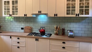 A kitchen with white cabinets, a red kettle, and a tiled backsplash. - Cosy Mountain retreat in a historic old gold mining town (Walhalla)