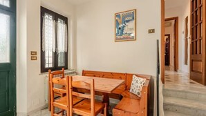 Un coin repas avec une table et des chaises en bois, un banc et une affiche accrochée au mur.