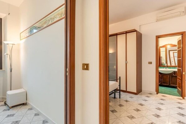 Hotelkamer met betegelde vloer, een bed, een kledingkast en een badkamer die door een open deur zichtbaar is.