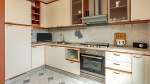Une cuisine de taille réduite avec des meubles blancs, une cuisinière, un four et un four à micro-ondes.