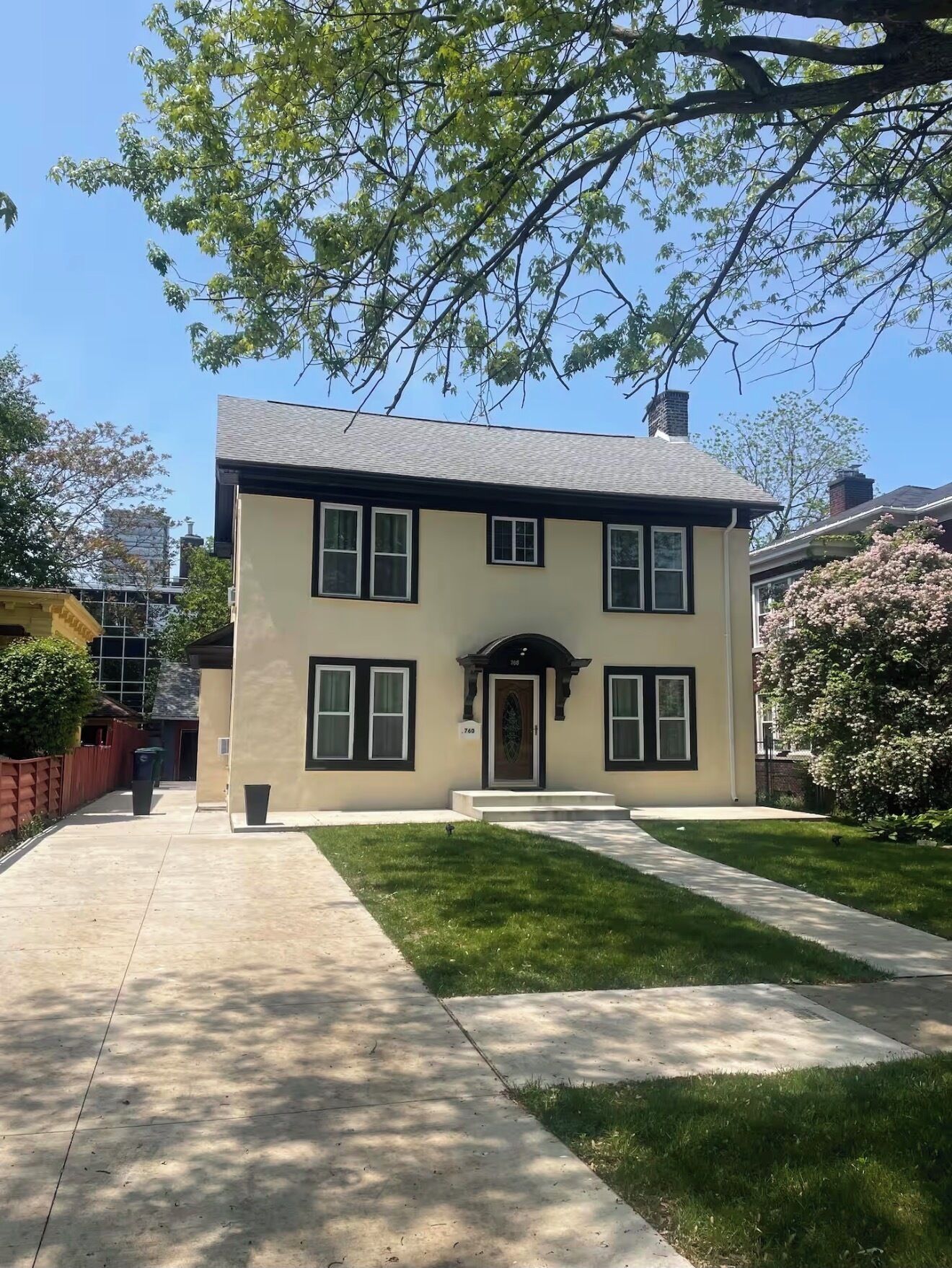 A two-story house with a front porch, a small front yard, and a clear sky.