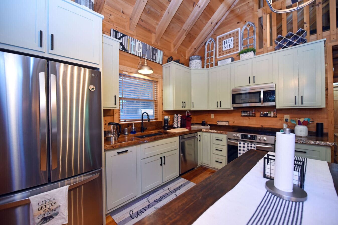 Una cocina moderna con electrodomésticos de acero inoxidable, armarios de colores claros y techo de madera.