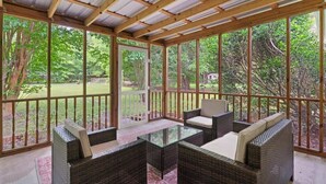 A covered patio with wicker furniture and glass tables, surrounded by a wooden railing and large windows. - Beachy Keen - Boat Ramp! (Brunswick)