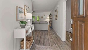 A hallway with a white console table, a grey sofa, and a wooden floor. - Beachy Keen - Boat Ramp! (Brunswick)